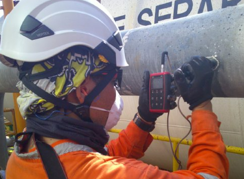 Técnico de AMC midiendo espesores con ultrasonido en una tubería de proceso